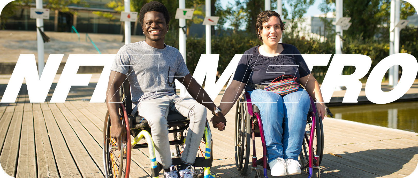 Two people in mobility devices, smiling and holding hands, in front of the words "NFTA METRO"